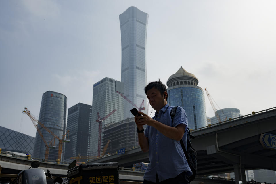 Pedestrians crosses an intersection with the background of the central business district in Beijing, China, Monday, July 15, 2024. China's ruling Communist Party is starting a four-day meeting Monday that is expected to lay out a strategy for self-sufficient economic growth in an era of heightened national security concerns and restrictions on access to American technology. (AP Photo/Vincent Thian)