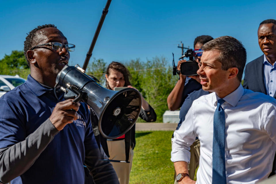 A man speaking through a bullhorn with another man in a shirt and tie