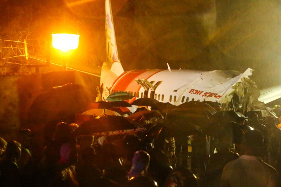 First responders gather around the wreckage of an Air India Express jet, which was carrying more than 190 passengers and crew from Dubai, after it crashed by overshooting the runway at Calicut International Airport in Karipur, Kerala, on August 7, 2020. - At least 14 people died and 15 others were critically injured when a passenger jet skidded off the runway after landing in heavy rain in India, police said on August 7. (Photo by Favas JALLA / AFP) (Photo by FAVAS JALLA/AFP via Getty Images)