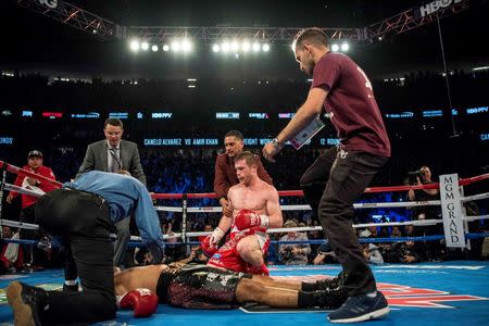 May 7, 2016; Las Vegas, NV, USA; Canelo Alvarez (red shorts) kneels down after knocking out Amir Khan (maroon shorts) during their middleweight boxing title fight at T-Mobile Arena. Mandatory Credit: Joshua Dahl-USA TODAY Sports