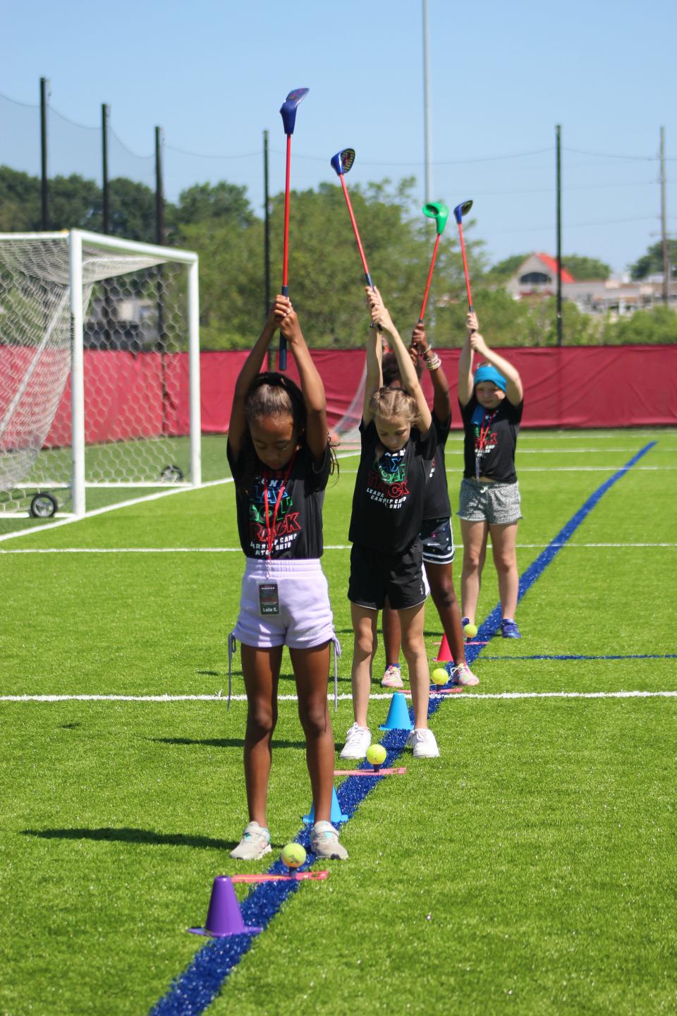 Young girls ready themselves to play golf on Malone's turf soccer field at the Pioneer Leadership/Exploratory Sports Camp on Thursday.