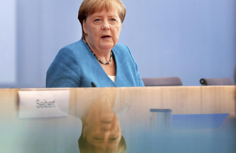 In this picture taken trough a window German Chancellor Angela Merkel addresses the media during her annual summer press conference in Berlin, Germany, Friday, Aug. 28, 2020. (AP Photo/Michael Sohn)