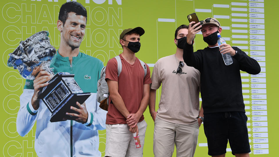 Spectators, pictured here taking selfies with a photo of Novak Djokovic as they arrive at Melbourne Park.