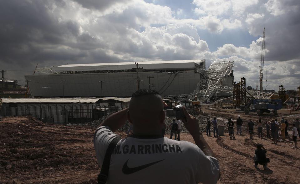 A man records the crane that collapsed on the site of the Arena Sao Paulo stadium, known as "Itaquerao", which will host the opening soccer match of the 2014 World Cup, in Sao Paulo