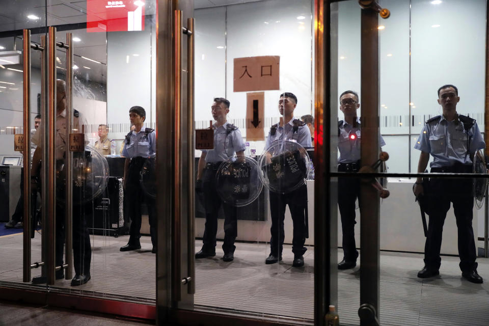 Police officers stand inside the entrance to police headquarters as protestors gather outside in Hong Kong, Friday, June 21, 2019. More than 1,000 protesters blocked Hong Kong police headquarters into the evening Friday, while others took over major streets as the tumult over the city's future showed no signs of abating. The mark on the wall is from an egg thrown by protestors. (AP Photo/Kin Cheung)