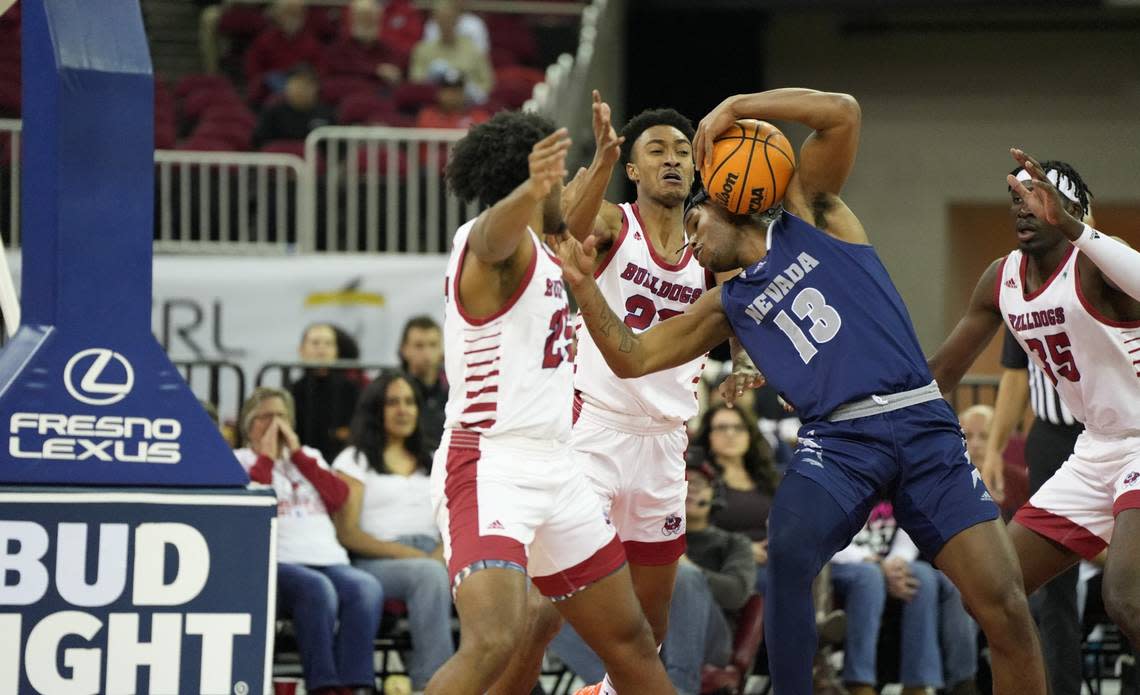 Fresno State forwards Anthony Holland (left) and Leo Colimerio defend Nevada’s Kenan Blackshear in the paint in the Bulldogs 60-56 loss to Nevada at the Save Mart Center on Friday, Feb. 24, 2023.