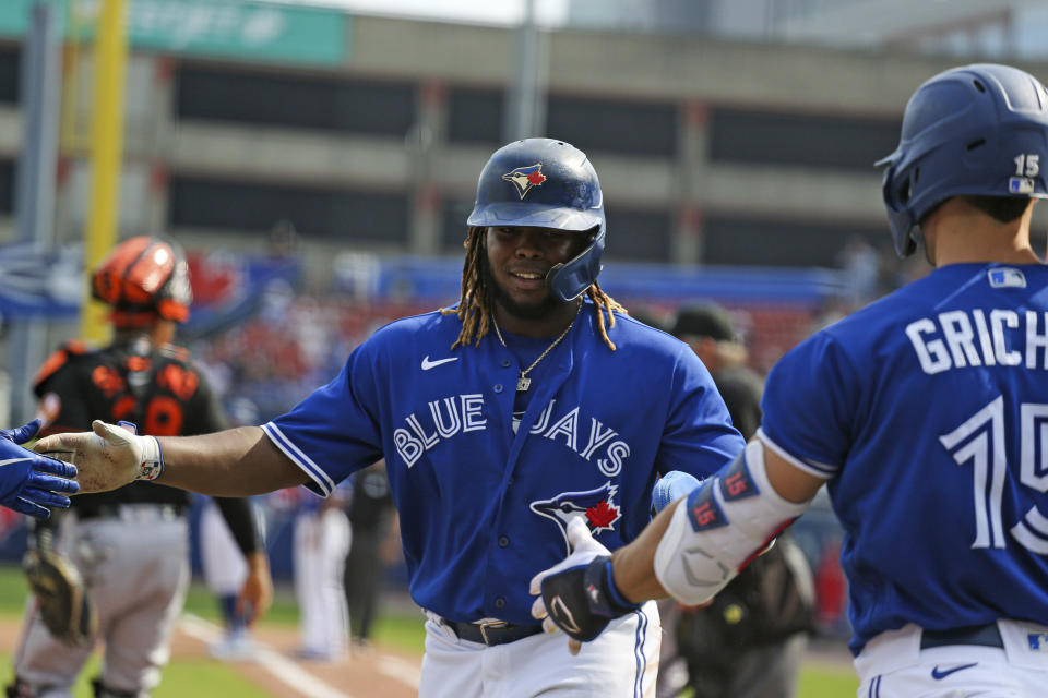 Toronto Blue Jays Vladimir Guerrero Jr., center, celebrates with Randal Grichuk, right, after scoring on a single by George Springer during the sixth inning of a baseball game against the Baltimore Orioles in Buffalo, N.Y., Saturday, June 26, 2021. (AP Photo/Joshua Bessex)