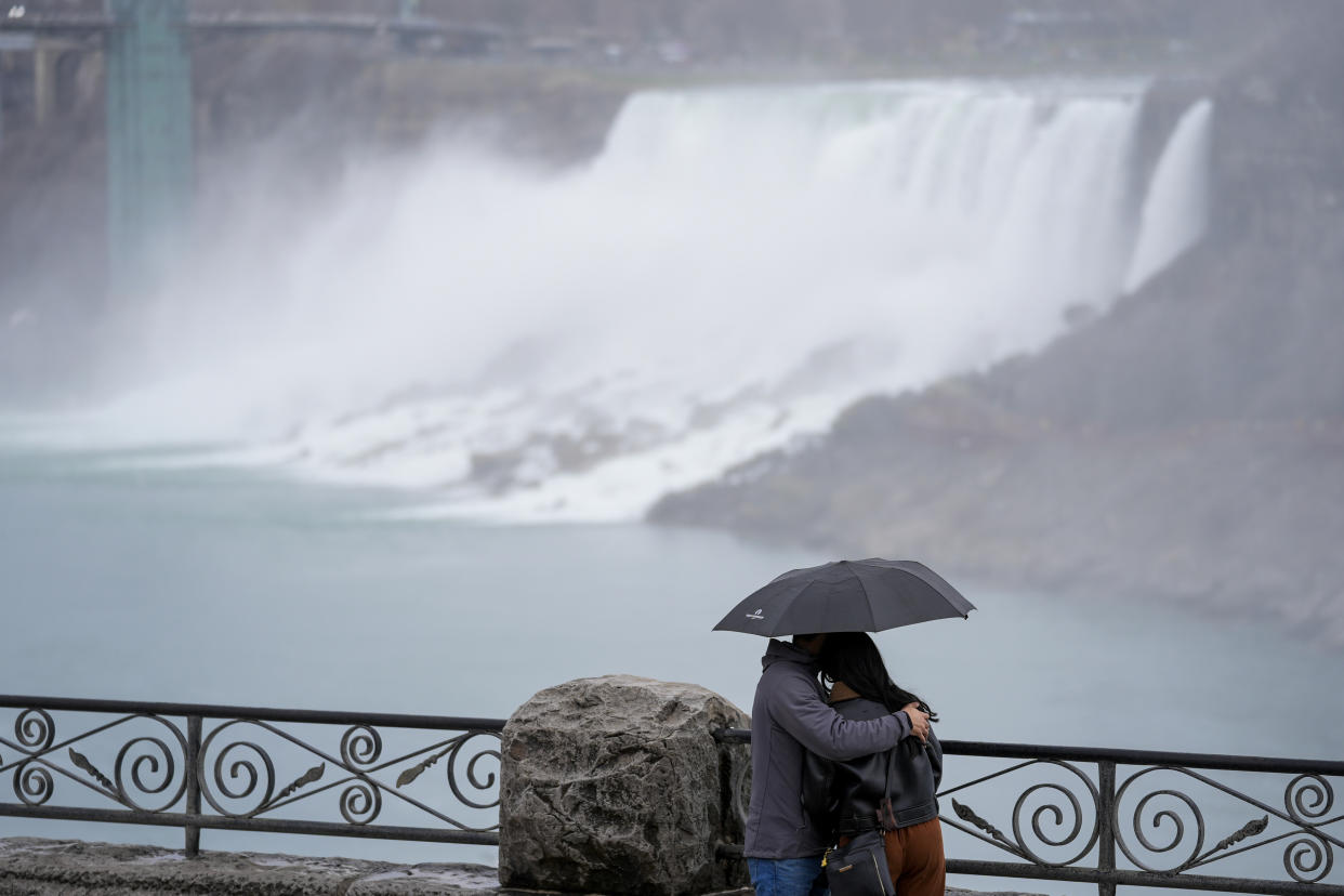 People gather under overcast skies ahead of a total solar eclipse in Niagara Falls, Ontario, Monday, April 8, 2024. (
