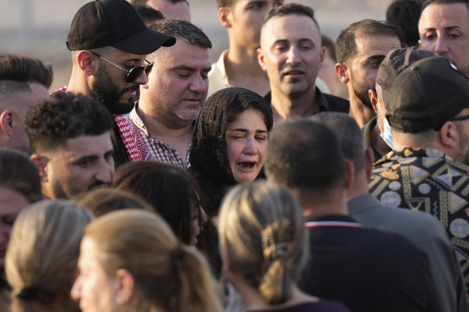 Friends and relatives attend the funeral of people who died in a fire during a wedding ceremony in Hamdaniya, Iraq, Wednesday, Oct. 27, 2023. A fire that raced through a hall hosting a Christian wedding in northern Iraq has killed around 100 people and injured 150 others, and authorities warn the death toll could rise. (AP Photo/Hadi Mizban