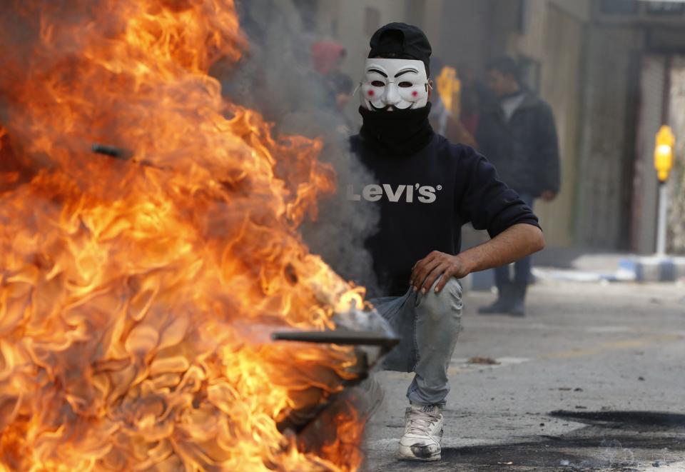 <p>A Palestinian protester wears a Guy Fawkes mask used by the anonymous movement during clashes with Israeli troops on Dec. 7, 2017 in Hebron in the Israeli-occupied West Bank, following protests against a decision by U.S. President Donald Trump to recognise Jerusalem as the capital of Israel. (Photo: Hazem Bader/AFP/Getty Images) </p>