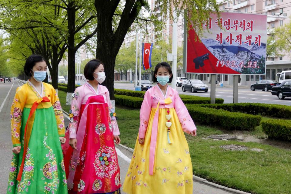 Women dressed in traditional Korean attire walk past a celebrative poster on the 90th founding anniversary of the Korean People's Revolutionary Army in Pyongyang, North Korea, Monday, April 25, 2022. The poster reads "Historic root of our revolution". (AP Photo/Jon Chol Jin)