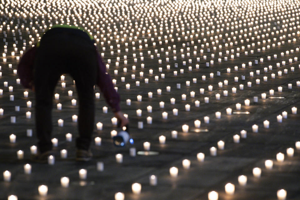 FILE - Activists light almost 9,200 candles to commemorate the people who have died of the coronavirus in Switzerland, Feb. 21, 2021, on the Bundesplatz, in front of the Federal Palace in Bern, Switzerland. Switzerland is facing an exponential rise in coronavirus cases. But its federal government, hasn't responded with new lockdown measures. Experts say that's because the government's anti-COVID policies face a crucial test at the ballot box. On Sunday Nov. 28, 2021, Swiss voters will cast ballots on a ‚COVID-19 law' that has unlocked billions of Swiss francs in aid for workers and businesses hit by the pandemic. (Peter Schneider/Keystone via AP, File)