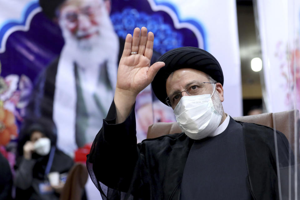 FILE - In this May 15, 2021 file photo, Ebrahim Raisi, head of Iran's judiciary, waves to journalists while registering his candidacy for the upcoming presidential elections, in Tehran, Iran. The presidential election on Friday, June 18, is likely to be a coronation for Raisi, a hard-line candidate long cultivated by Supreme Leader Ayatollah Ali Khamenei, shown in poster. (AP Photo/Ebrahim Noroozi, File)