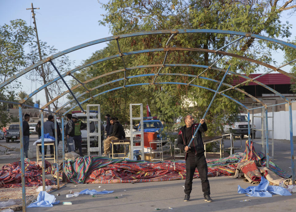 Pro-Iranian militiamen and their supporters dismantle a tent in front of the U.S. Embassy, in Baghdad, Iraq, Wednesday, Jan. 1, 2020. U.S. troops fired tear gas on Wednesday to disperse pro-Iran protesters who were gathered outside the U.S. Embassy compound in Baghdad for a second day. (AP Photo/Nasser Nasser)