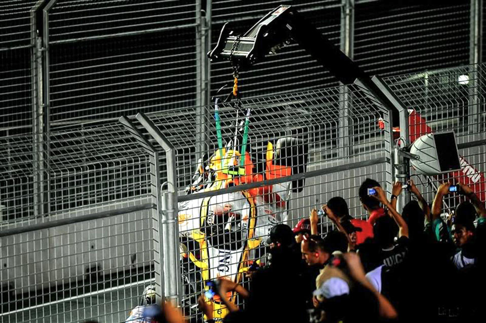 Renault Formula One auto racing driver Brazil's Nelson Piquet Jr.'s car is lifted by a crane while fans watch and take pictures at the Singapore Formula One Grand Prix on the Marina Bay City Circuit in Singapore on Sept. 28, 2008. (Lisa Hee / AP file)