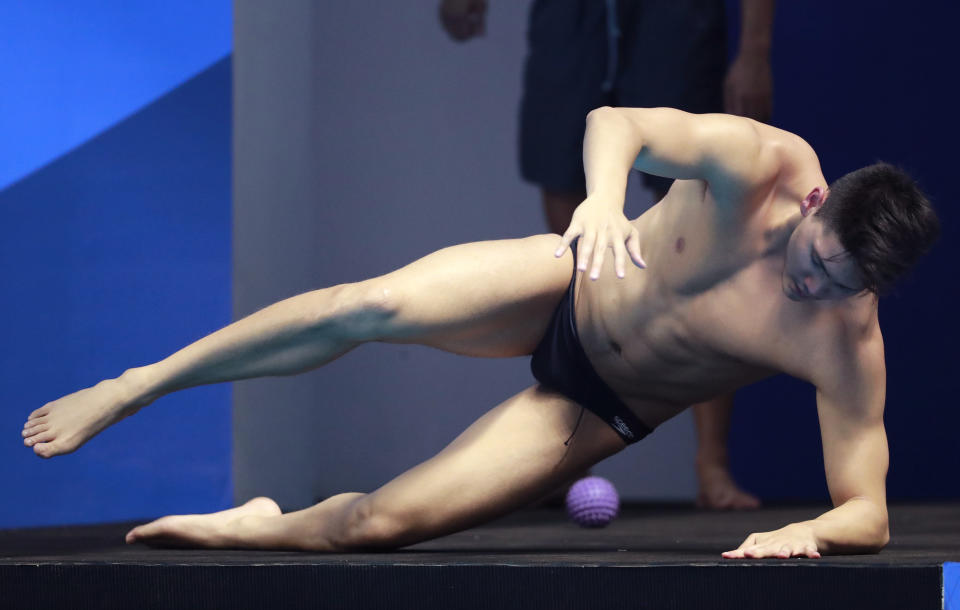 Singapore's Joseph Schooling performs some stretching exercises ahead of a training session at the 18th Asian Games in Jakarta, Indonesia, Friday, Aug. 17, 2018. (AP Photo/Bernat Armangue )