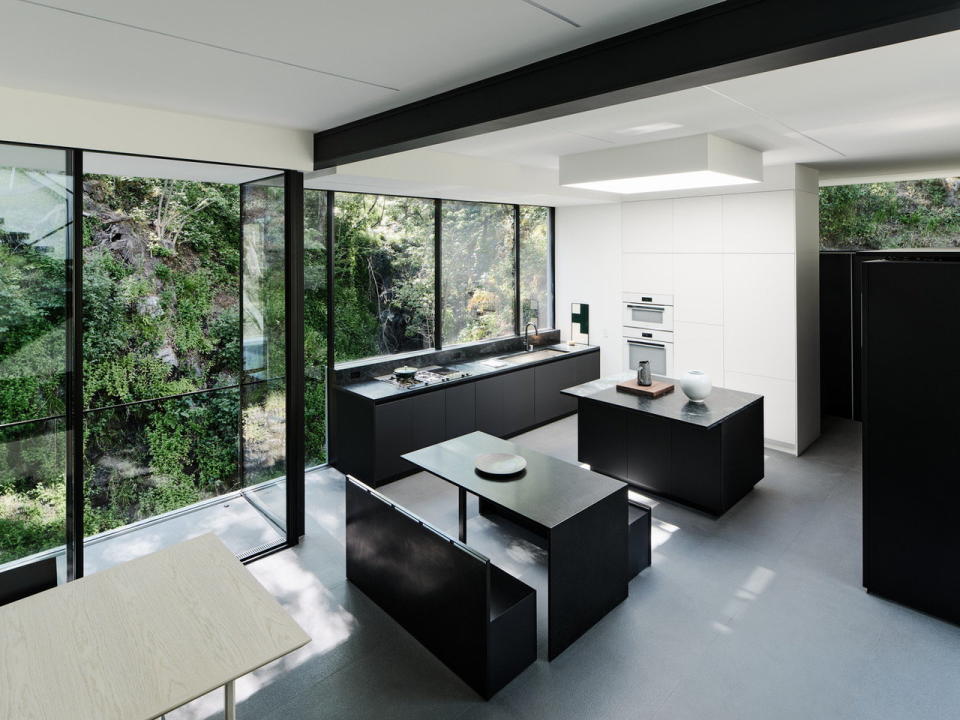 Minimalist kitchen space inside California's renovated Suspension House, complete with an island and banquette seating.