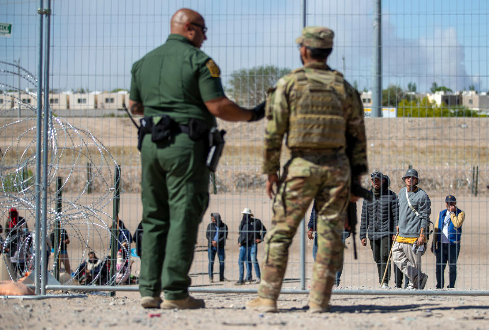 Migrants wait in line adjacent to the border fence under the watch of the Border Patrol and Texas National Guard to enter into El Paso, Texas, on May 10, 2023.  (Andres Leighton / AP)