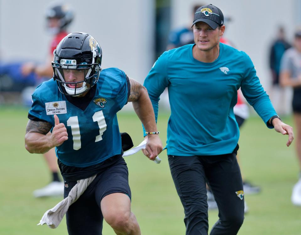 F/A-18 Super Hornet looks on as Jacksonville Jaguars wide receiver Parker Washington (11) runs a route during passing drills at the Jacksonville Jaguars Friday morning training camp session July 28, 2023 inside the Miller Electric Center training facility.