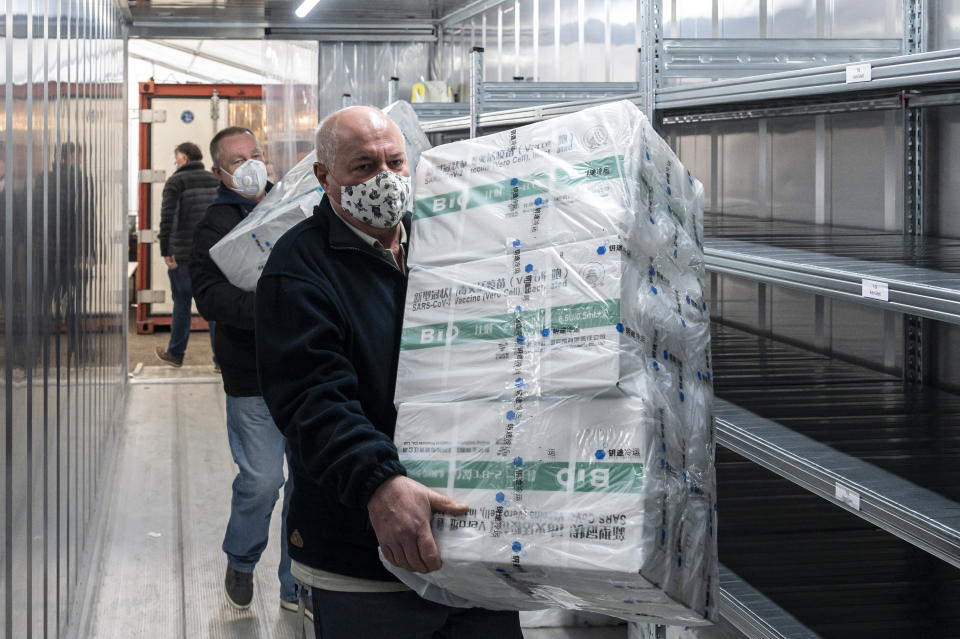 Employees unload the newly arrived coronavirus vaccines from Chinese pharmaceutical company Sinopharm at the logistics base set up to in the parking lot of the government office in the 13th district of Budapest, Hungary, March 3, 2021. (Zsolt Szigetvary/MTI via AP)