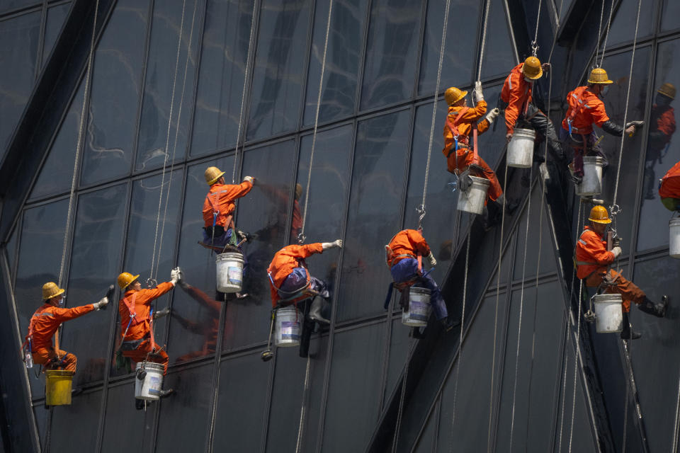 Workers wearing face masks hang from ropes as they wash windows on the China Central Television (CCTV) building in Beijing, Wednesday, May 4, 2022. Beijing on Wednesday closed around 10% of the stations in its vast subway system as an additional measure against the spread of coronavirus. (AP Photo/Mark Schiefelbein)