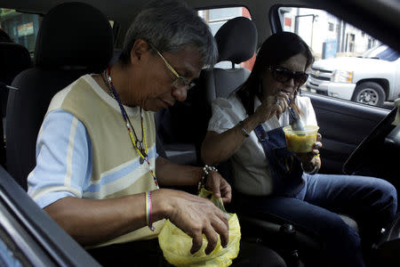 Sonia Moreno and her husband have lunch in their car as they wait for gas near a gas station of the Venezuelan state-owned oil company PDVSA in San Cristobal, Venezuela November 10, 2018. REUTERS/Carlos Eduardo Ramirez