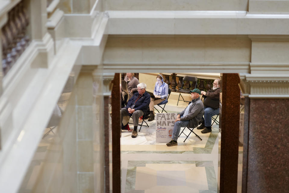 People gather to watch the Wisconsin Supreme Court redistricting hearing on a television in the rotunda of the Wisconsin state Capitol Building in Madison, Wis., on Tuesday, Nov. 21, 2023. (Ruthie Hauge/The Capital Times via AP, Pool)