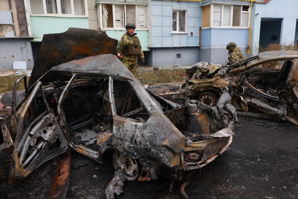 Self-defence unit volunteers stand by burned-out cars in a residential area of the city of Belgorod following fresh aerial attacks on March 22 (AFP via Getty)