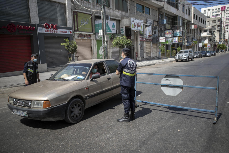 Palestinian Hamas policemen stop vehicles during a lockdown imposed following the discovery of coronavirus cases in the Gaza Strip, Thursday, Aug. 27, 2020. On Wednesday Gaza's Hamas rulers extended a full lockdown in the Palestinian enclave for three more days as coronavirus cases climbed after the detection this week of the first community transmissions of the virus in the densely populated, blockaded territory. (AP Photo/Khalil Hamra)