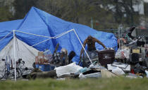 A man is seen in a homeless encampment on Thursday, March 19, 2020, in Oakland, Calif. California governor Gavin Newsom has authorized $150 million in emergency funding to protect homeless people in California from the spread of COVID-19. $100 million will go to local governments for shelter support and emergency housing, while the remaining $50 million will be for purchasing travel trailers and lease rooms in hotels, motels and other facilities to provide places for the homeless to self-isolate. (AP Photo/Ben Margot)