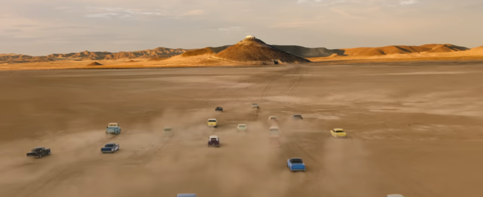 Several vintage cars driving through the desert