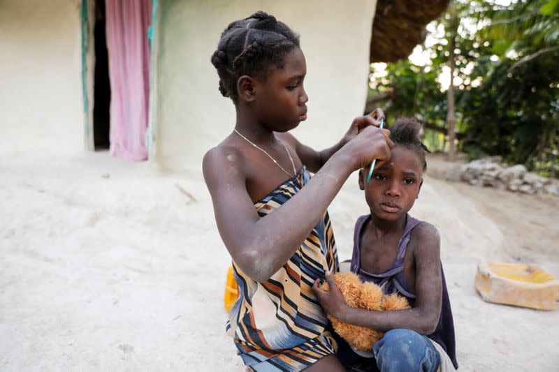 Two girls, daughters of Celavi Belor, spend time together outside their house in Jean-Rabel