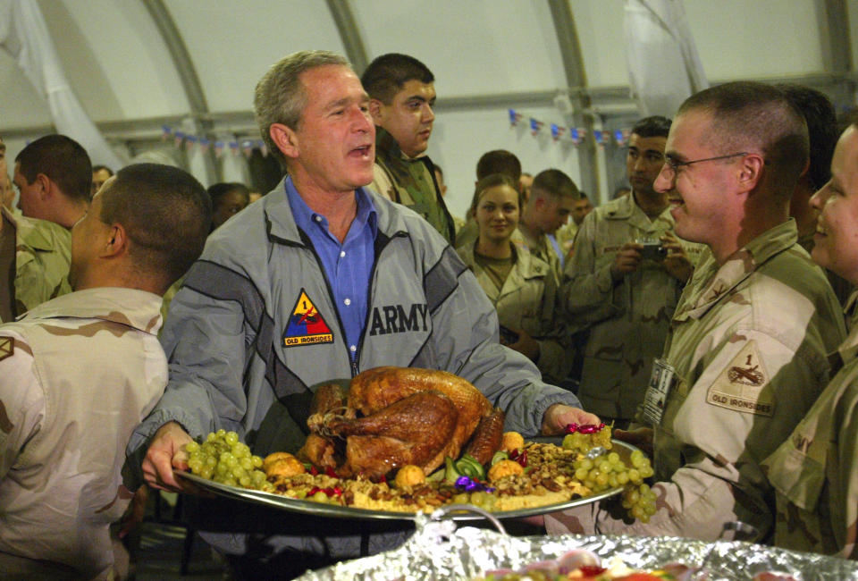 FILE - In this Thursday, Nov. 27, 2003 file photo, U.S. President George W. Bush carries a platter of turkey and fixings as he visits U.S. troops for Thanksgiving in Baghdad. Anja Niedringhaus, a courageous and immensely talented Associated Press photographer who has covered everything from sports to war, was killed while covering elections in Afghanistan on Friday April 4, 2014. Niedringhaus was in a car in eastern Afghanistan with AP reporter Kathy Gannon when, according to a freelancer who was with them, an Afghan policeman approached them, yelled "Allahu Akbar" - God is Great -and opened fire on them in the back seat with his AK-47. Niedringhaus was killed instantly and Gannon was wounded. (AP Photo/Anja Niedringhaus, File)