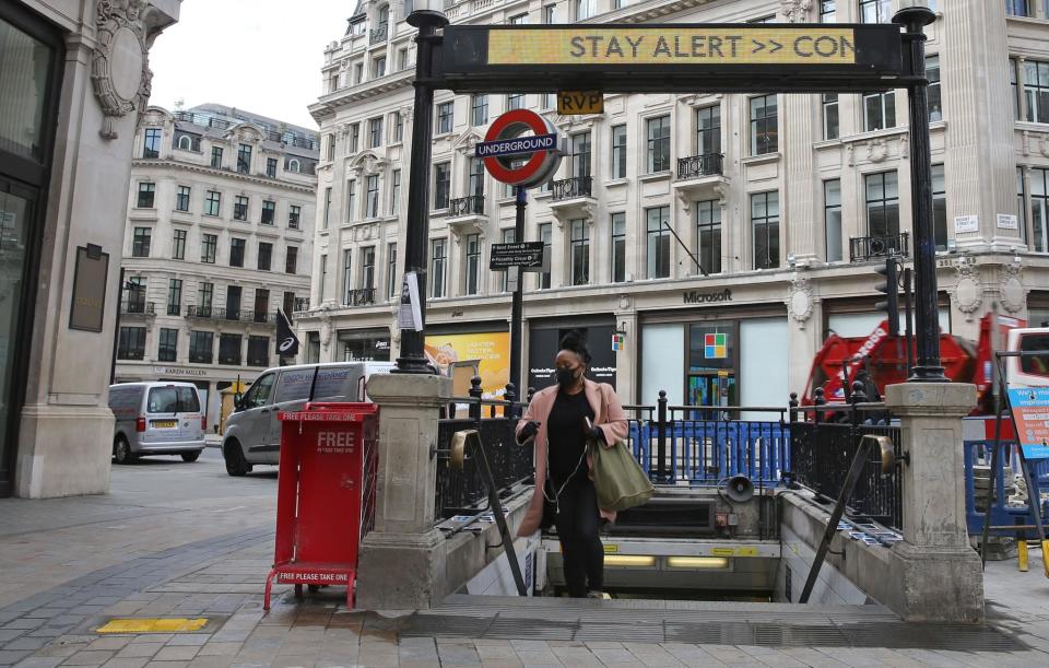 A commuter wearing PPE passes beneath the government's slogan: 'Stay Alert, Control the Virus, Save Lives' above the exit to Oxford Circus Underground station in central London (Getty)