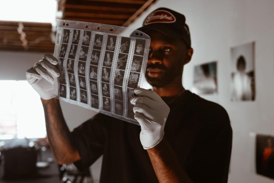 Black man holding up negative black and white photo prints with white gloves