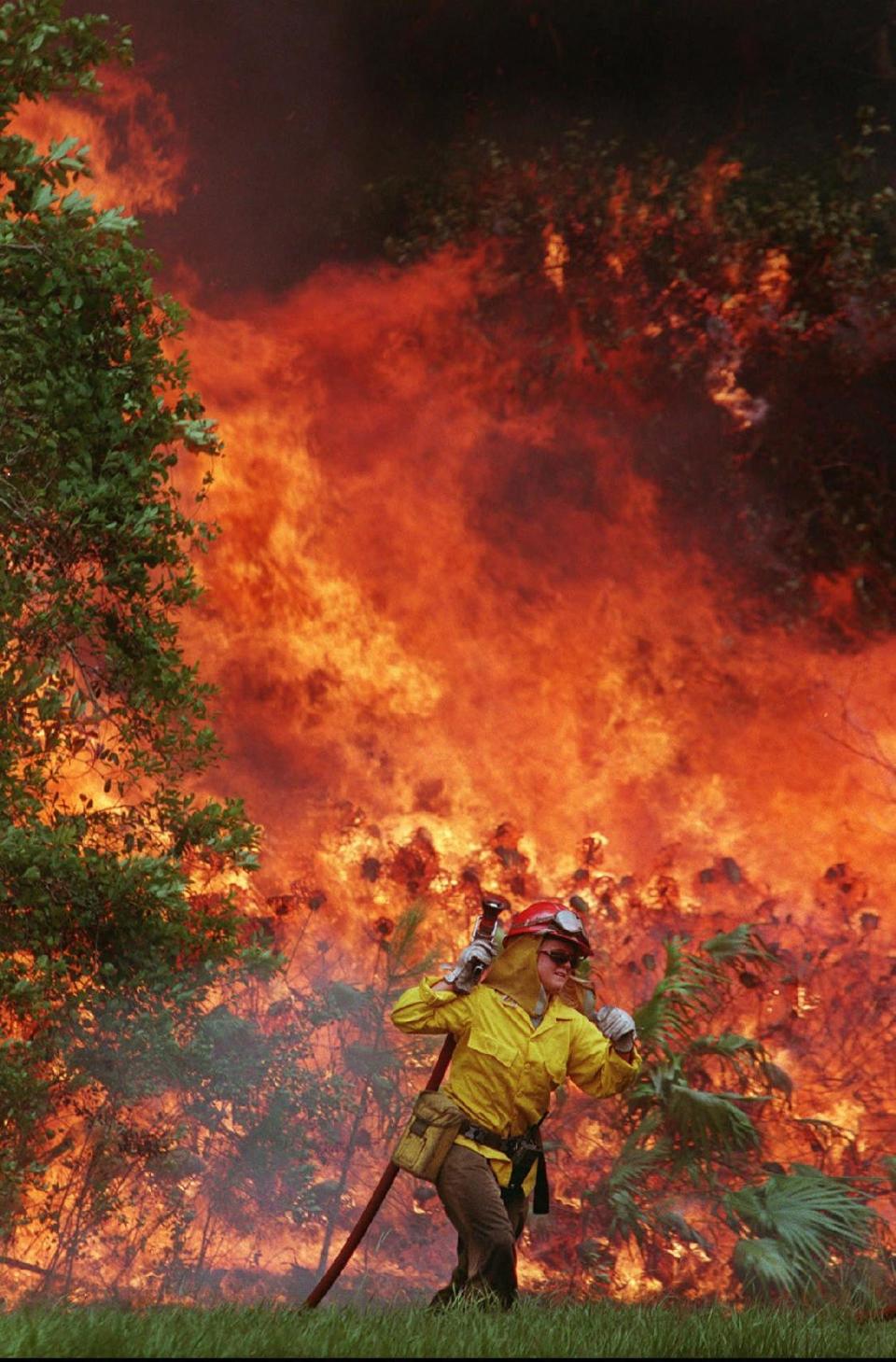 Firefighter Amy Midgett, with the North Carolina Fish & Game Commission, retreats from a wall of flames along US-92 just west of Daytona Beach, on Sunday, June 28, 1998. Similar fires ravaged the Kennedy Space Center in Brevard County. KSC firefighters used firefighting foams now known to cause health and environmental threats to save structures at the space center, including the South Repeater Building.