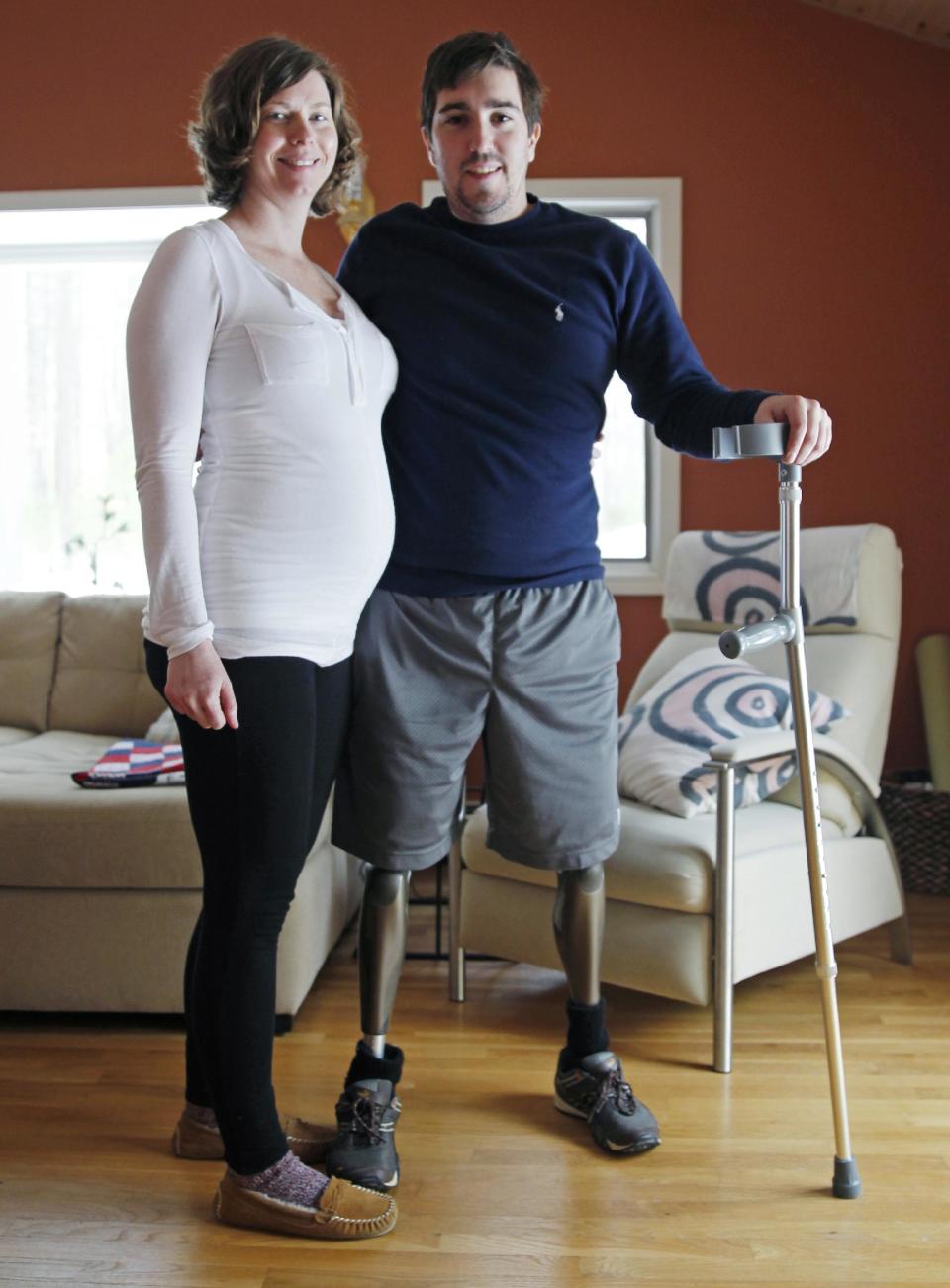 Jeff Bauman, who lost both legs in the Boston Marathon bombings, then helped authorities identify the suspects, poses with his expectant fiancé, Erin Hurley, their home in Carlisle, Mass., Friday, March 14, 2014. According to Bauman, the baby is due July 14. They don’t know if it’s a boy or a girl, and they want it to be a surprise. The two were engaged in February. (AP Photo/Charles Krupa)