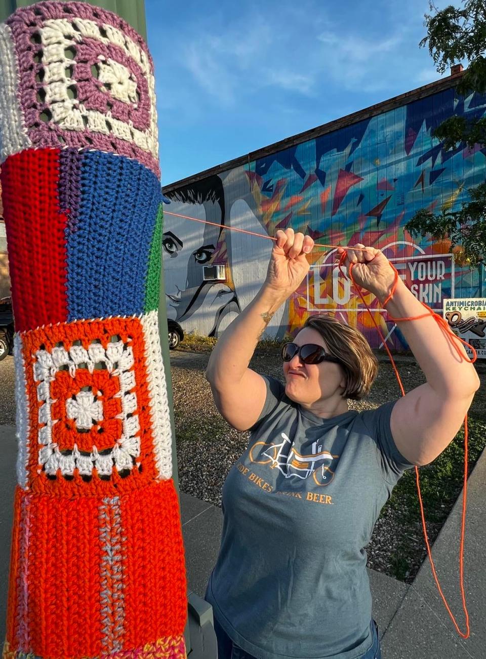 Volunteer Carla Giacobone works on yarn art on Sixth Street NW in downtown Canton. Yarn art will decorate poles and buildings, including in the Court Avenue NW area.