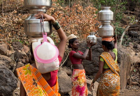 A woman helps another in carrying metal pitchers filled with water from a well outside Denganmal village, Maharashtra, April 20, 2015. REUTERS/Danish Siddiqui