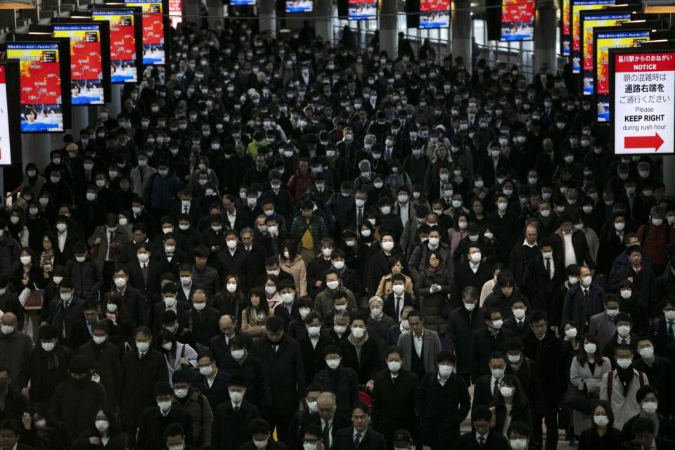 A large crowd of mask-wearing commuters