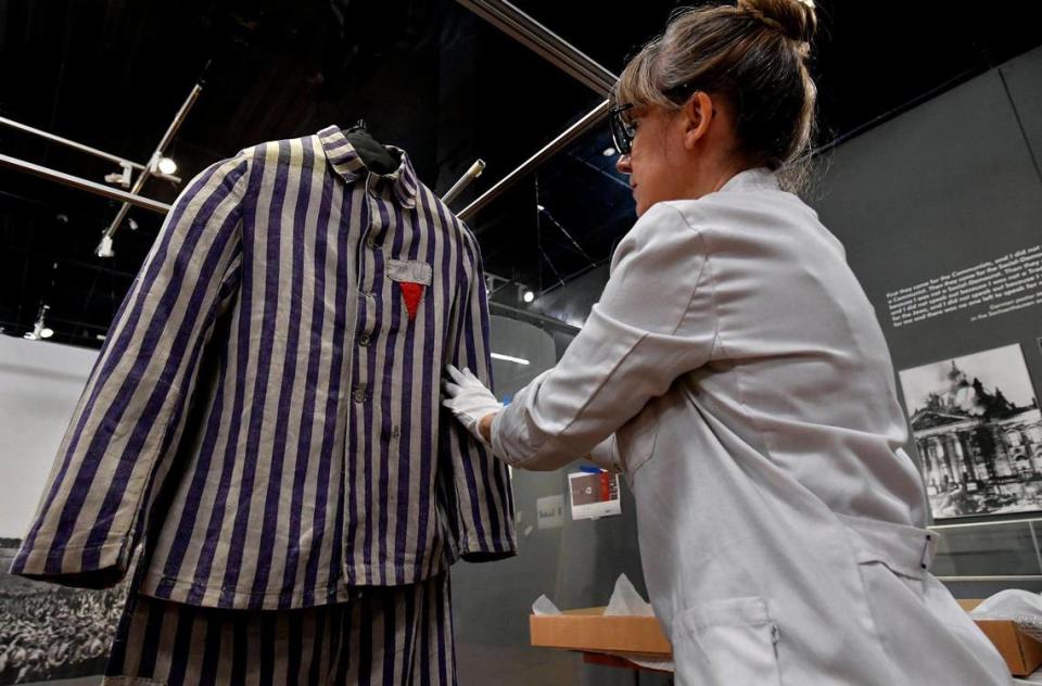 Aná Galan, a collections manager for Musealia, installs a prisoner’s jacket and pants that are part of “Auschwitz. Not Long Ago. Not Far Away.” Her company, based in Spain, helped conceive the exhibition, which opens June 14 at Union Station.