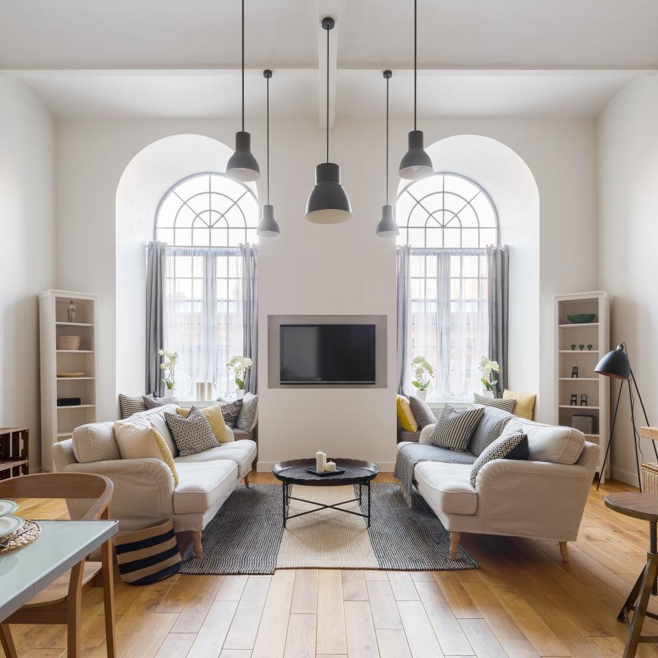 A white-walled living room with large arch windows  and two couches across from each other 