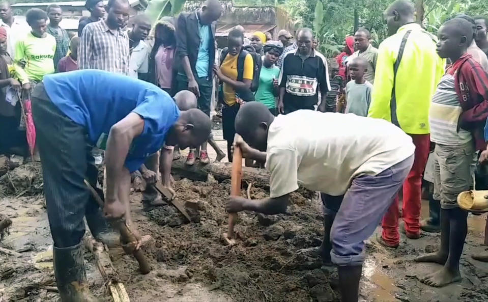 In this image made from video, residents dig in the mud in Bududa District, Uganda, Friday, Oct. 12, 2018. At least 30 people died in mudslides triggered by torrential rains in a mountainous area of eastern Uganda that is prone to such disasters, a Red Cross official said Friday. More victims were likely to be discovered when rescue reams access all the affected areas in the foothills of Mount Elgon, said Red Cross spokeswoman Irene Nakasiita. (AP Photo)