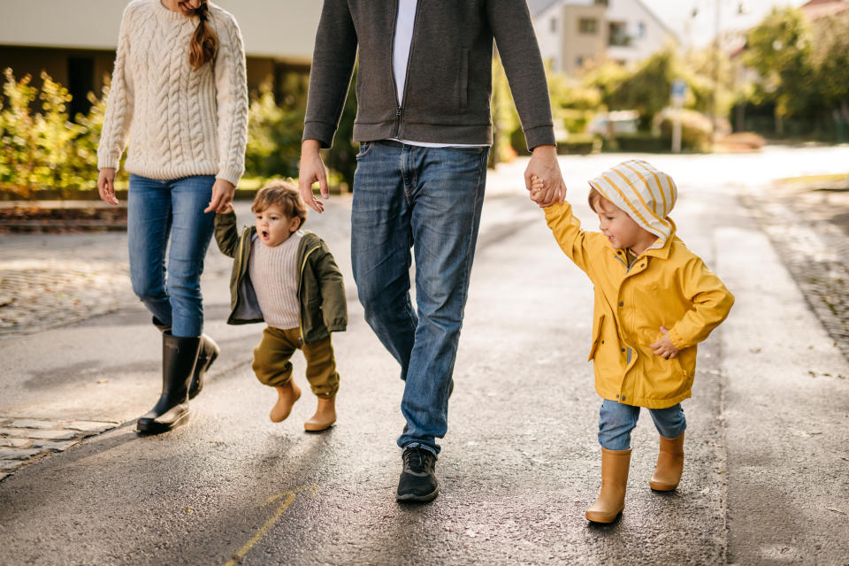 Family with a child walking hand in hand, viewed from the waist down