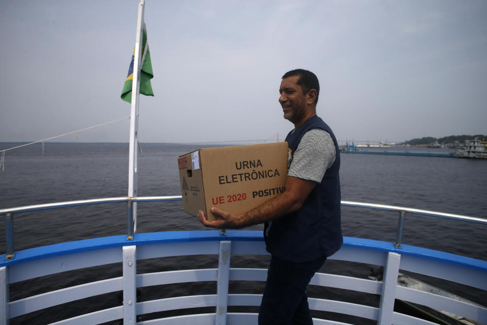 An electoral worker carries an electronic voting machine on a boat to a voting center ahead of tomorrow's elections at the Sao Raimundo port, Manaus, Amazonas state, Brazil, Saturday, Oct.1, 2022. (AP Photo/Edmar Barros)