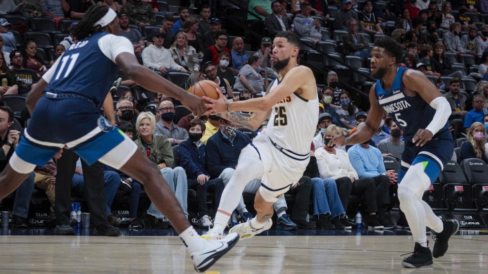 Denver Nuggets guard Austin Rivers (25) drives between Minnesota Timberwolves' Naz Reid (11) and Malik Beasley (5) during the second half of a preseason NBA basketball game in Denver, Friday, Oct. 8, 2021. (AP Photo/Joe Mahoney)