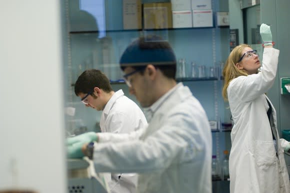 Scientists in white labcoats working in a lab.