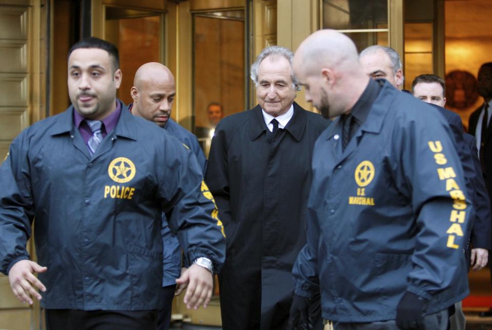 FILE - Disgraced financier Bernard Madoff, center, leaves U.S. District Court in Manhattan escorted by U.S. Marshals after a bail hearing in New York, Monday, Jan. 5, 2009. More than 12 years after Madoff confessed to running the biggest financial fraud in Wall Street history, a team of lawyers is still at work on a sprawling effort to recover money for the thousands of victims of his scam. (AP Photo/Kathy Willens, File)