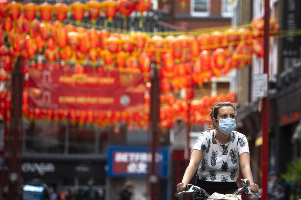 A woman wearing a face mask cycles through Chinatown, central London, as the UK continues in lockdown to help curb the spread of the coronavirus.