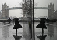 FILE - In this Thursday, Jan. 14, 2021 file photo, a woman is reflected in a window as she braves the wind and rain while walking towards Tower Bridge in London, during England's third national lockdown to curb the spread of coronavirus. Thanks to an efficient vaccine roll out program and high uptake rates, Britain is finally saying goodbye to months of tough lockdown restrictions. From Monday May 17, 2021, all restaurants and bars can fully reopen, as can hotels, cinemas, theatres and museums, and for the first time since March 2020, Britons can hug friends and family and meet up inside other people’s houses. (AP Photo/Kirsty Wigglesworth, File)